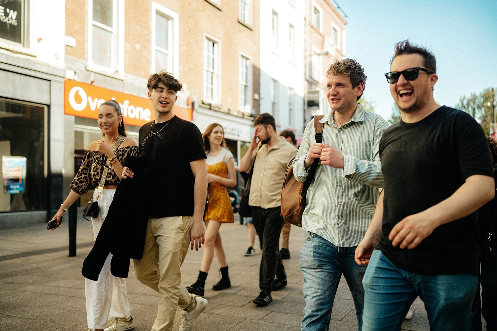 Three men smiling and walking together down a street during a photography tour