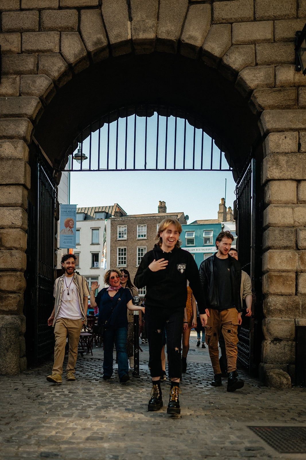 Guide smiling as he leads his tour group through a large metal gateway