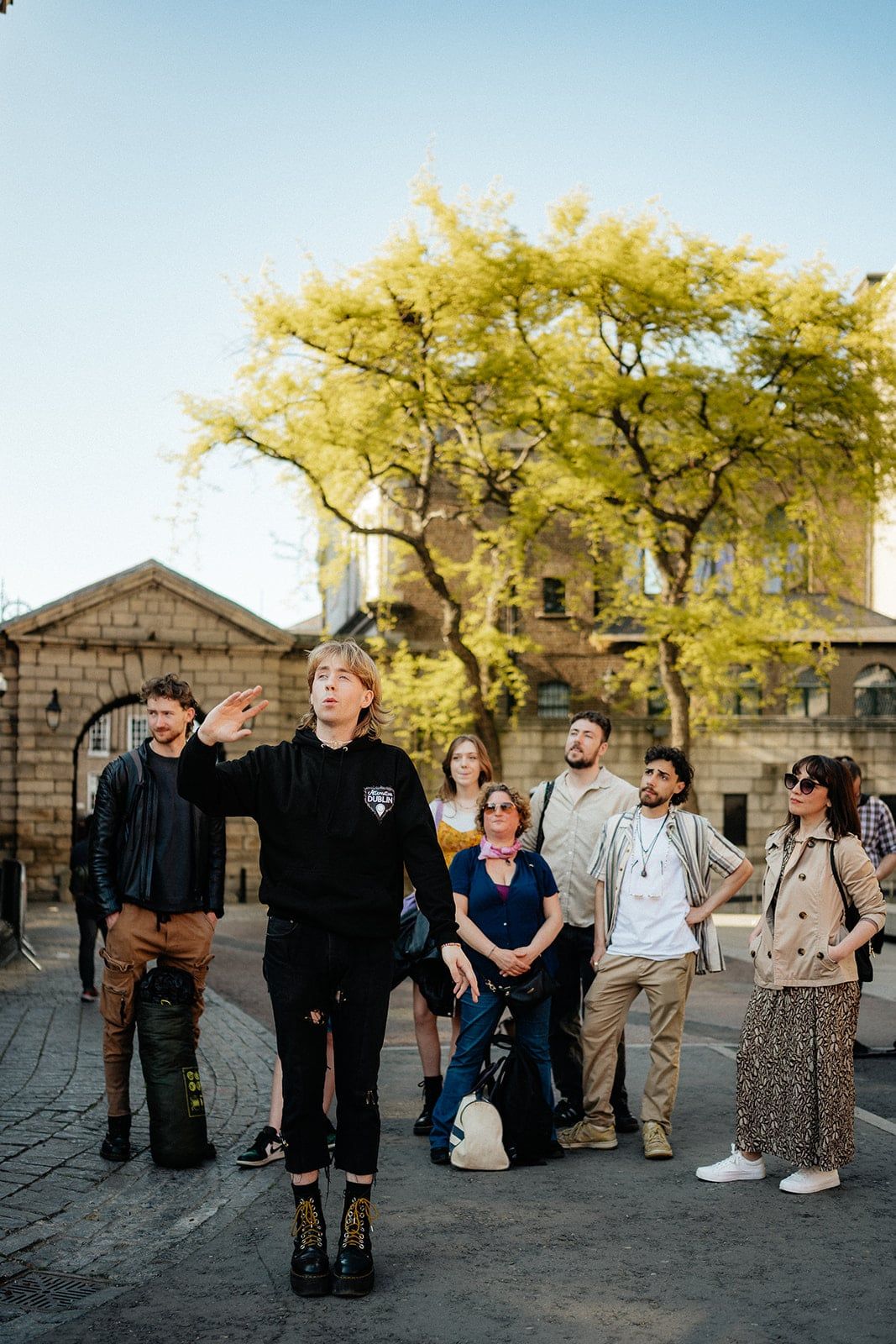 Tour guide gesturing while explaining a location to his group on a sunny day