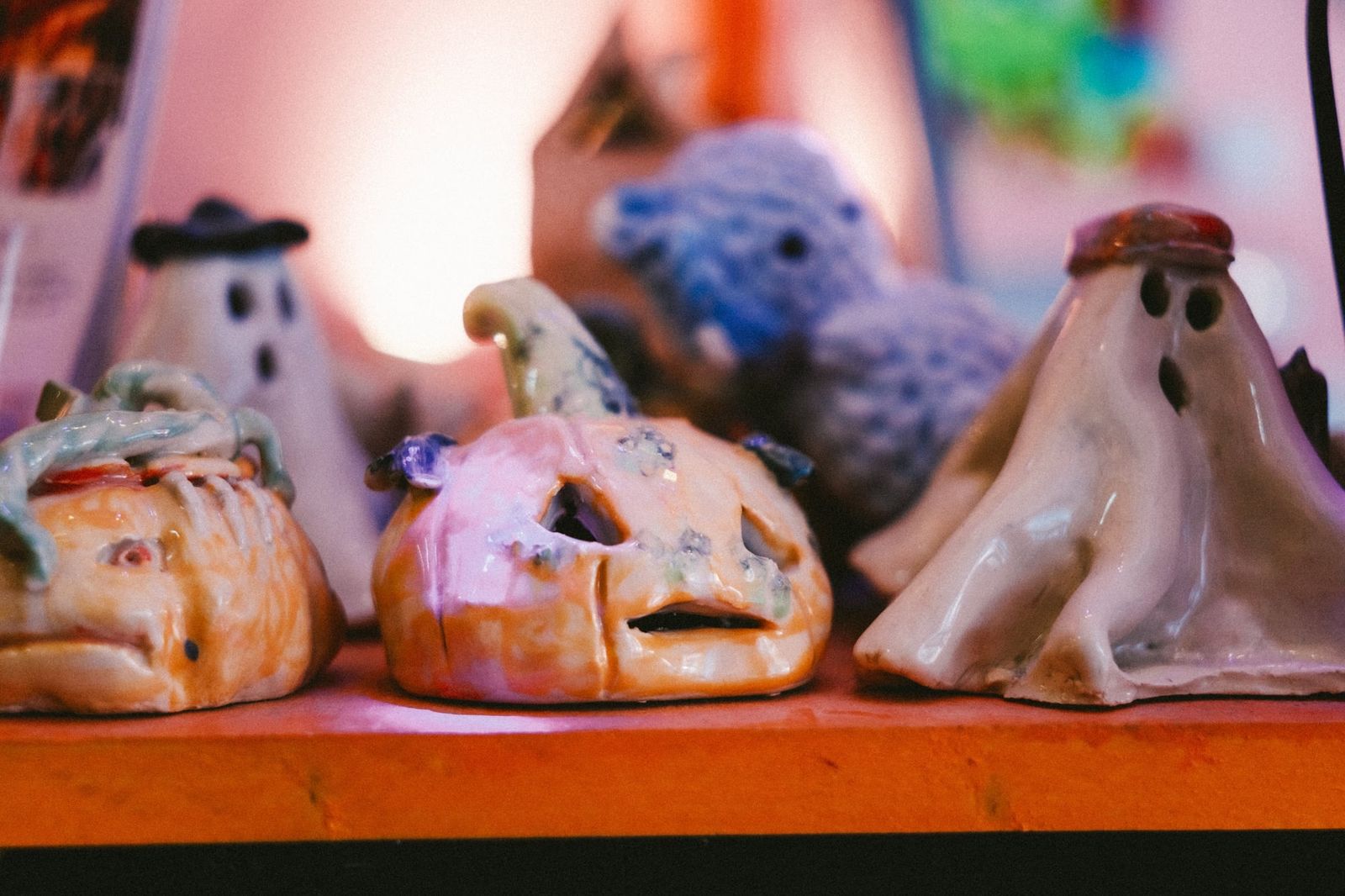 Several small handmade clay ghost and pumpkin figurines from a pottery workshop