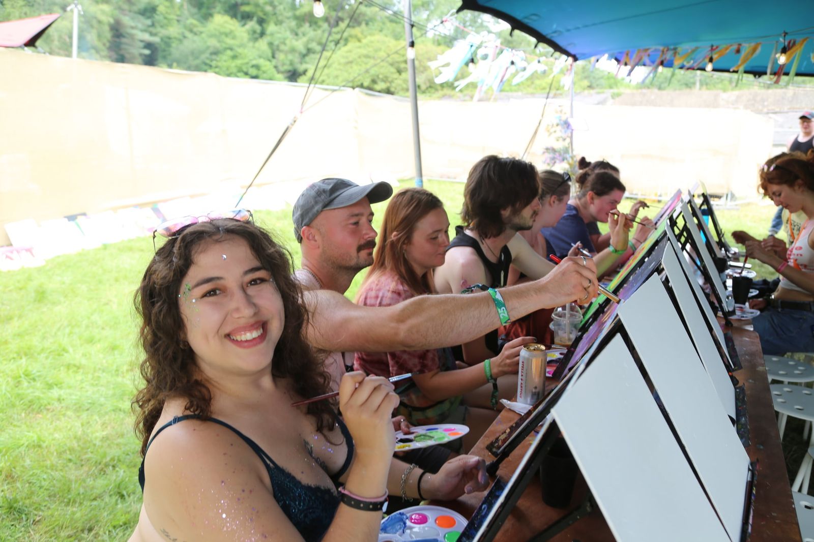 Smiling guest looking back from her canvas at an outdoor paint and sip event