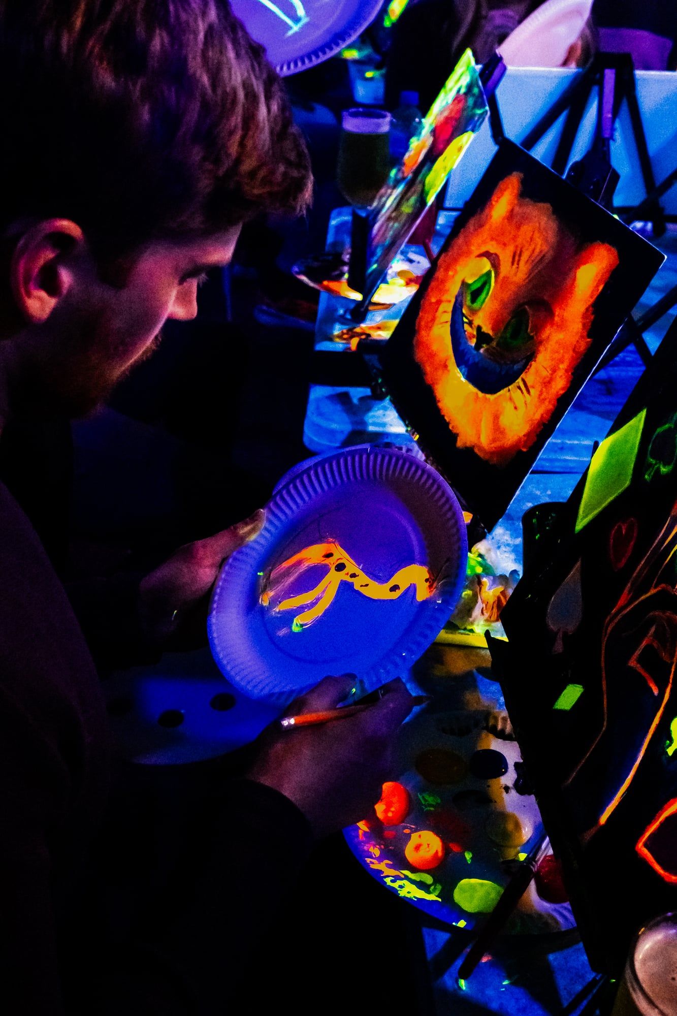 Guest painting glowing orange and yellow shapes on a paper plate palette