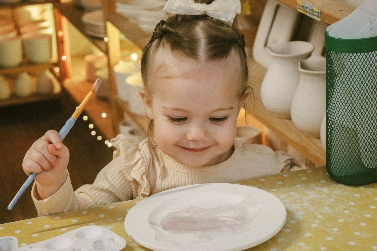 Young girl happily mixing paint on a plate at a family pottery event