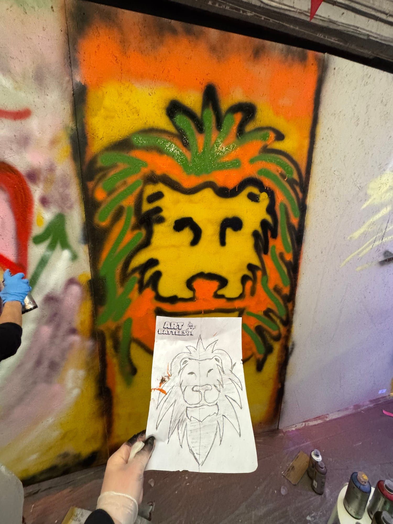 Close-up of a stencil and finished yellow graffiti lion face on a wooden board