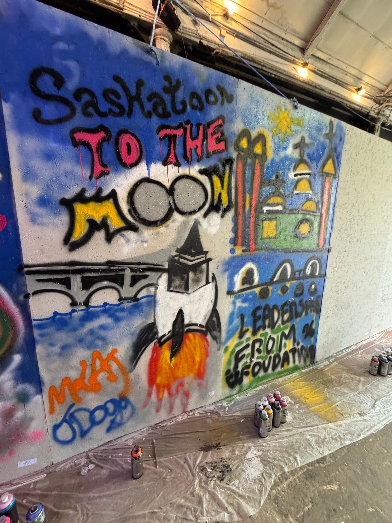 Colorful finished graffiti artwork featuring a rocket and buildings on a textured wall