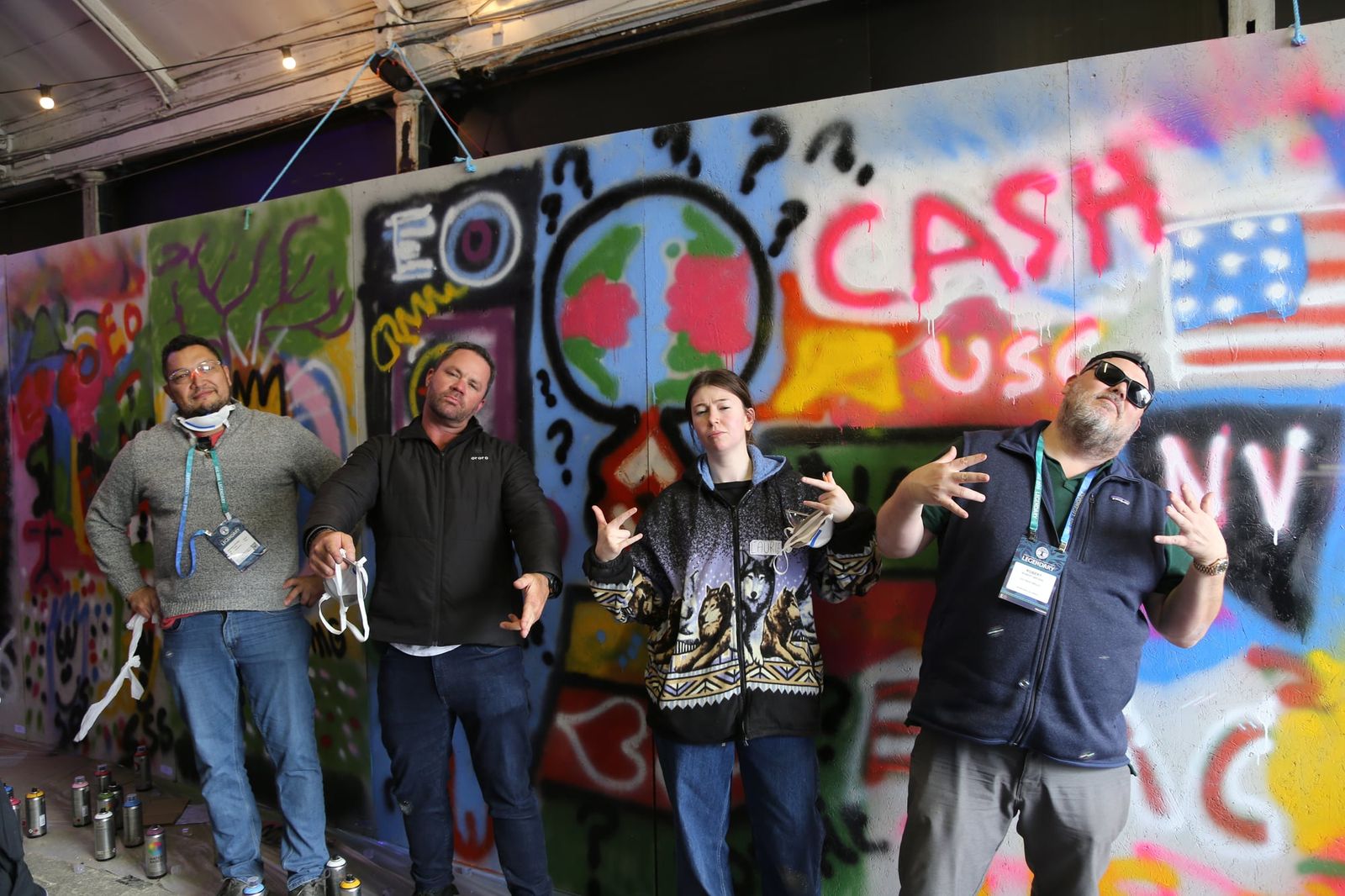 Group of four guests posing in front of a colorful wall at a graffiti event