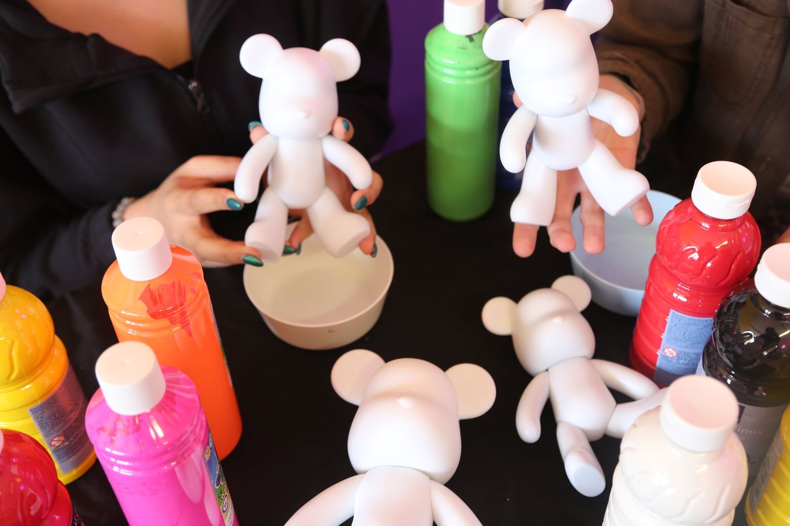 Guests holding blank bear figurines ready for painting at a workshop