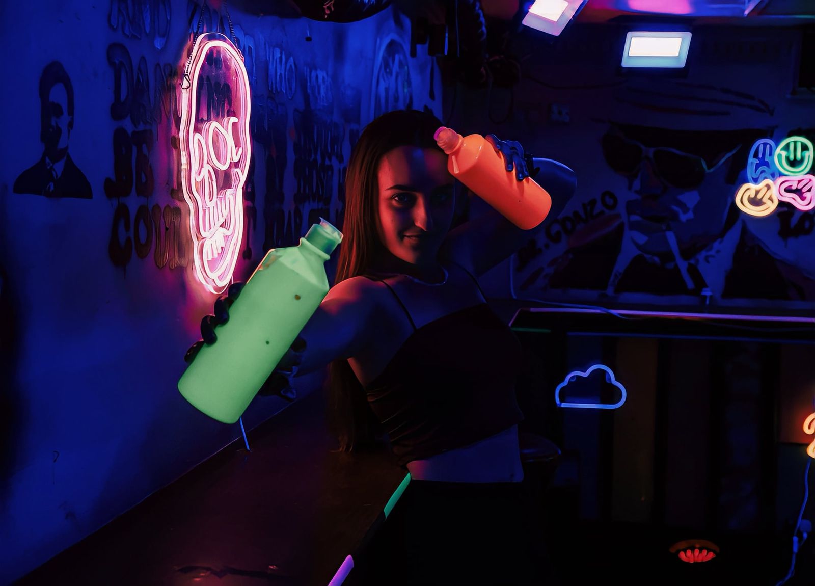 Guest posing with neon paint bottles under blacklights at a glow in the dark event