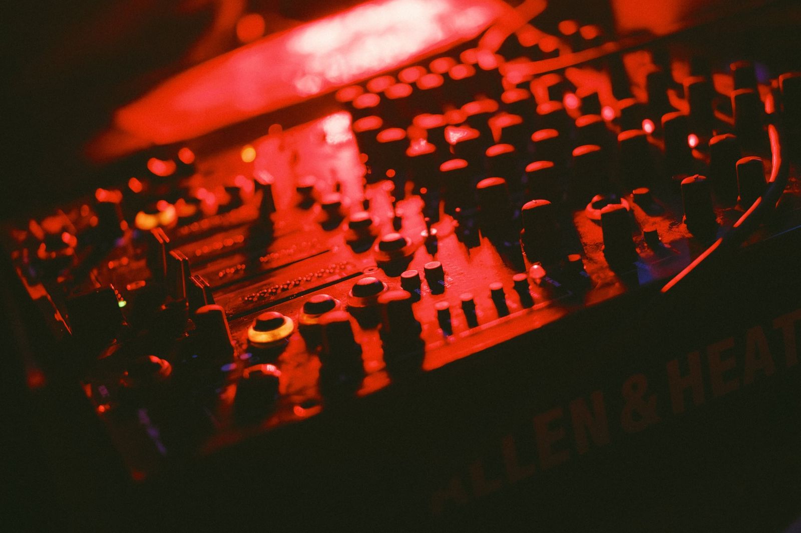DJ mixing board illuminated by red lighting at a neon painting event
