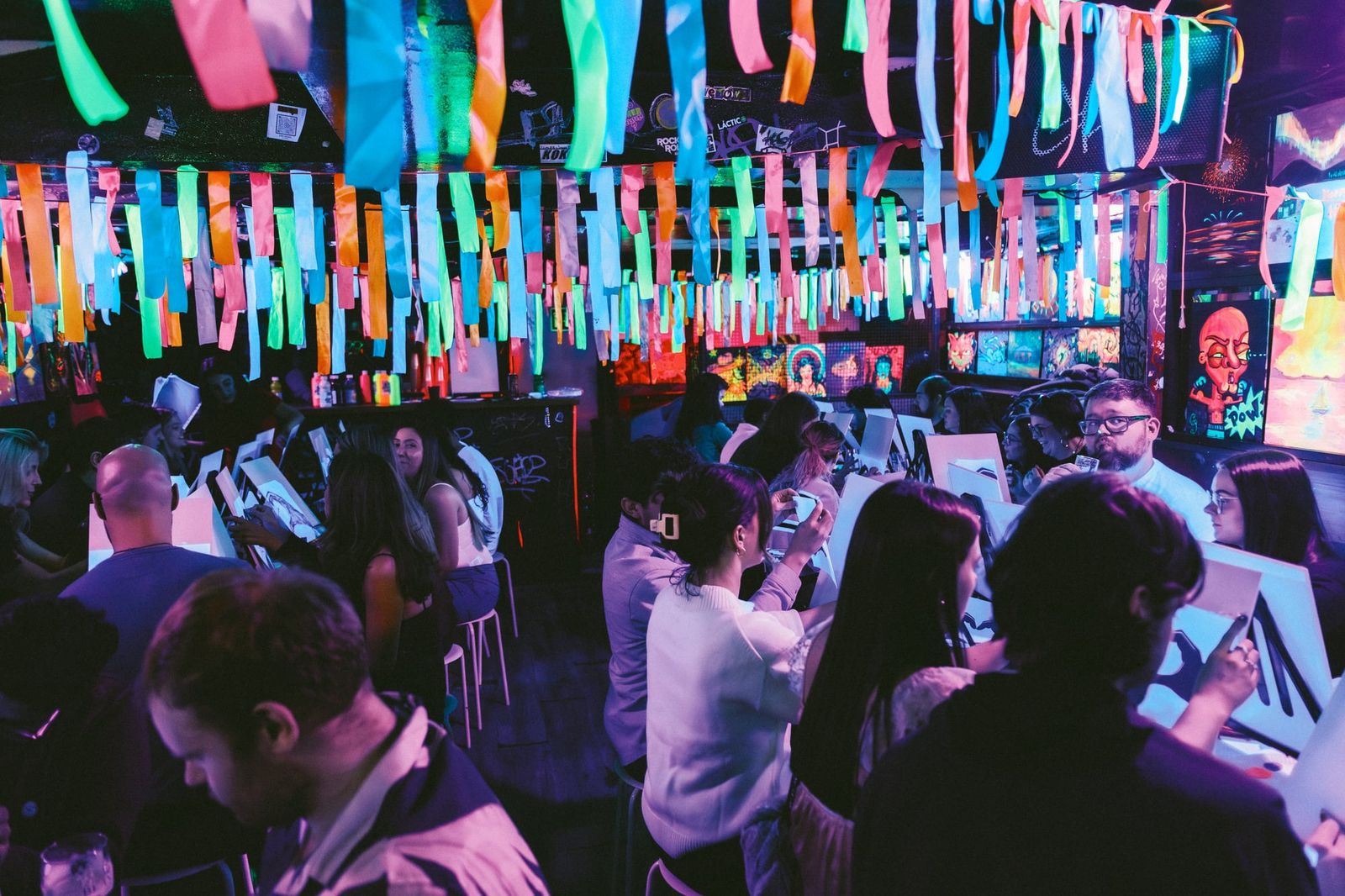 Guests gathered at tables in a lively room filled with neon lights and decorations
