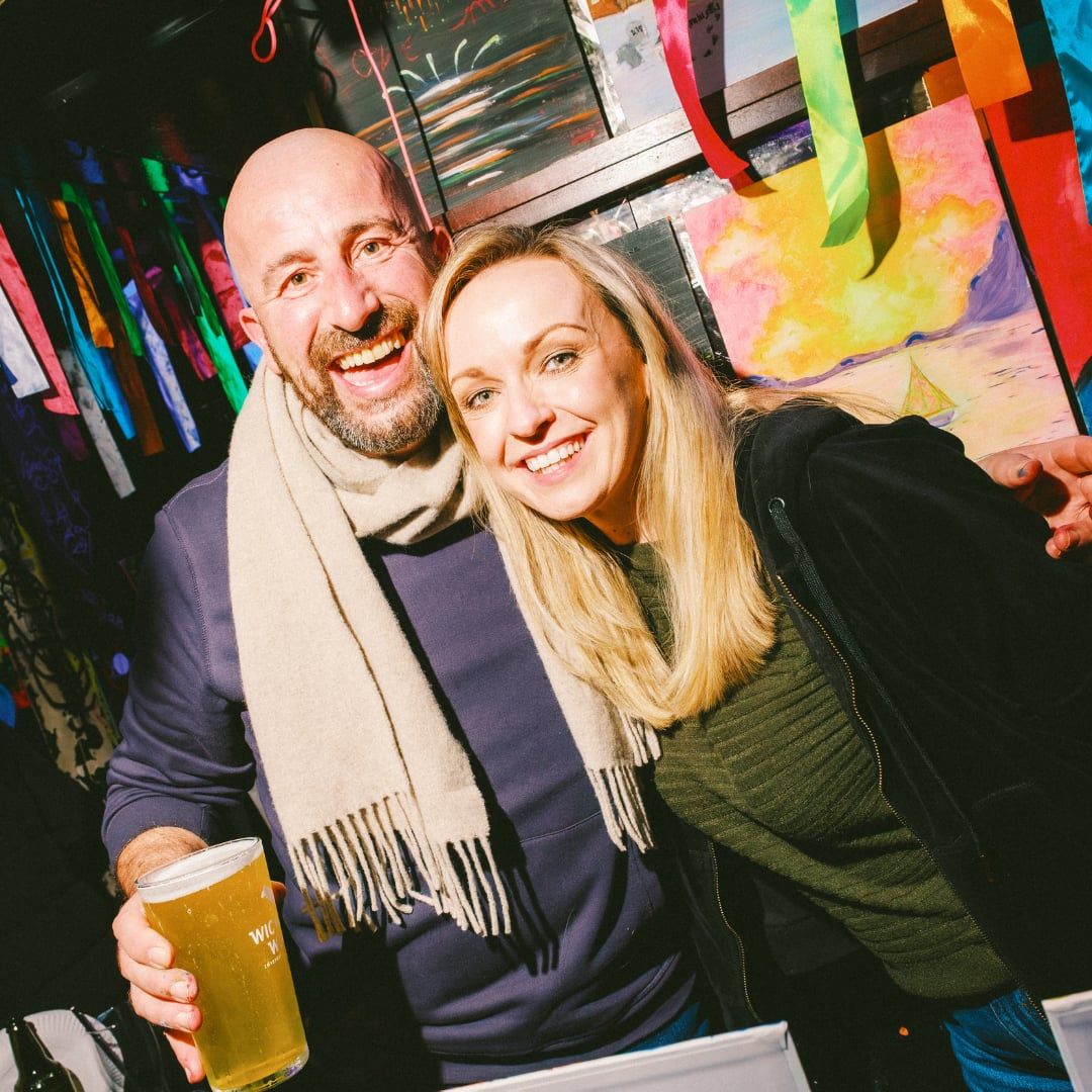 Man and woman smiling for a photo together at a neon painting workshop