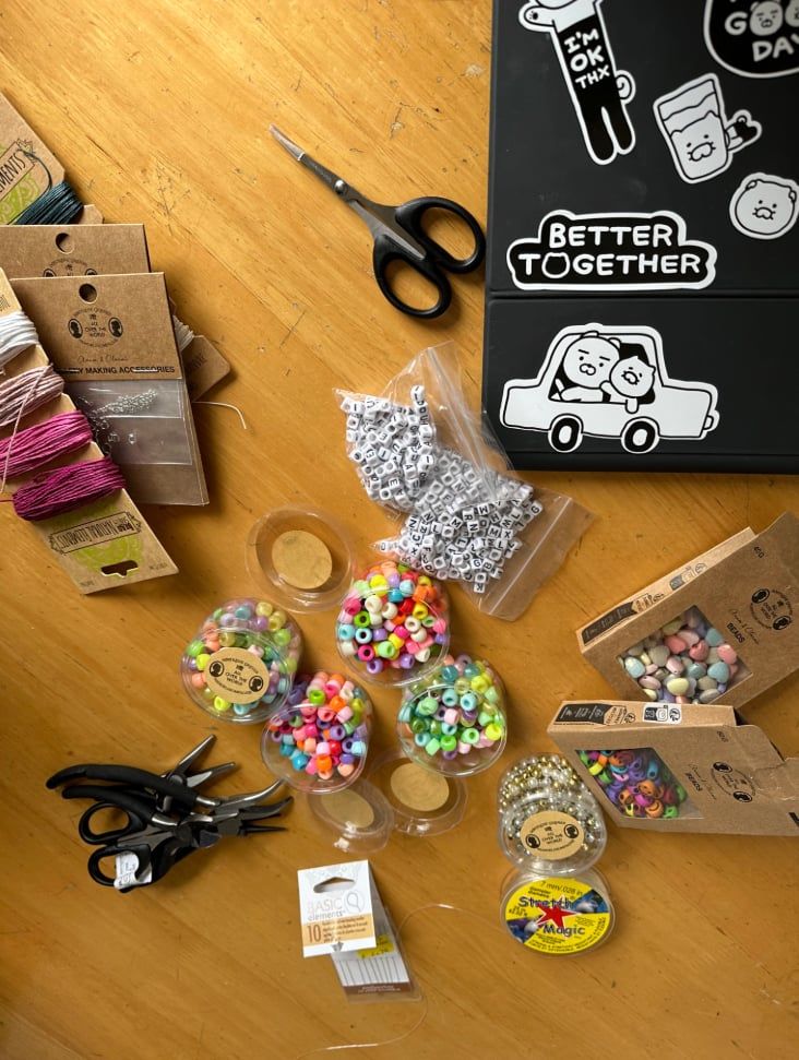 Various beads, strings, and jewellery making supplies laid out on a table