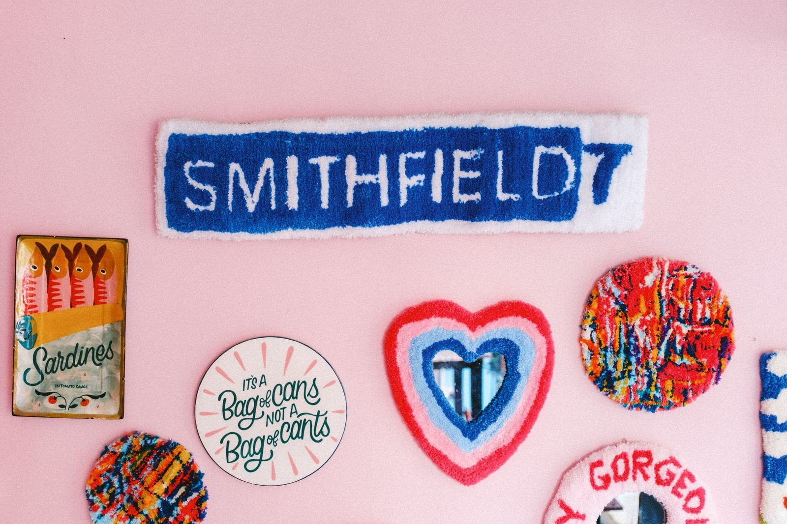 Colorful finished tufted rug pieces including a Smithfield sign and a heart