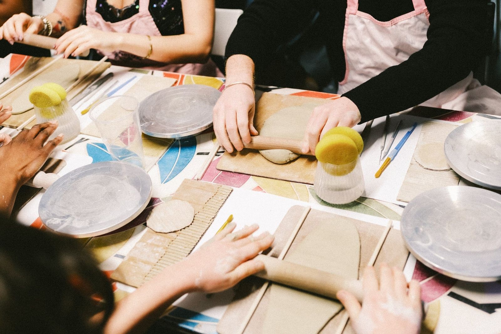 Guests using rolling pins to flatten slabs of clay at a pottery workshop