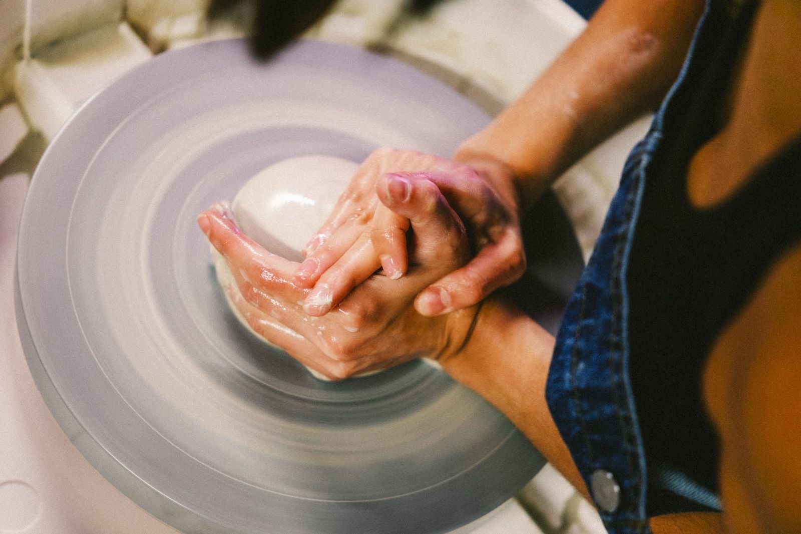 Overhead view of hands centering wet clay on a spinning pottery wheel