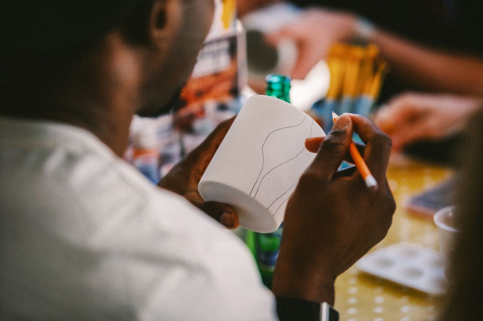 Guest sketching a design onto a blank ceramic cup at a pottery painting class