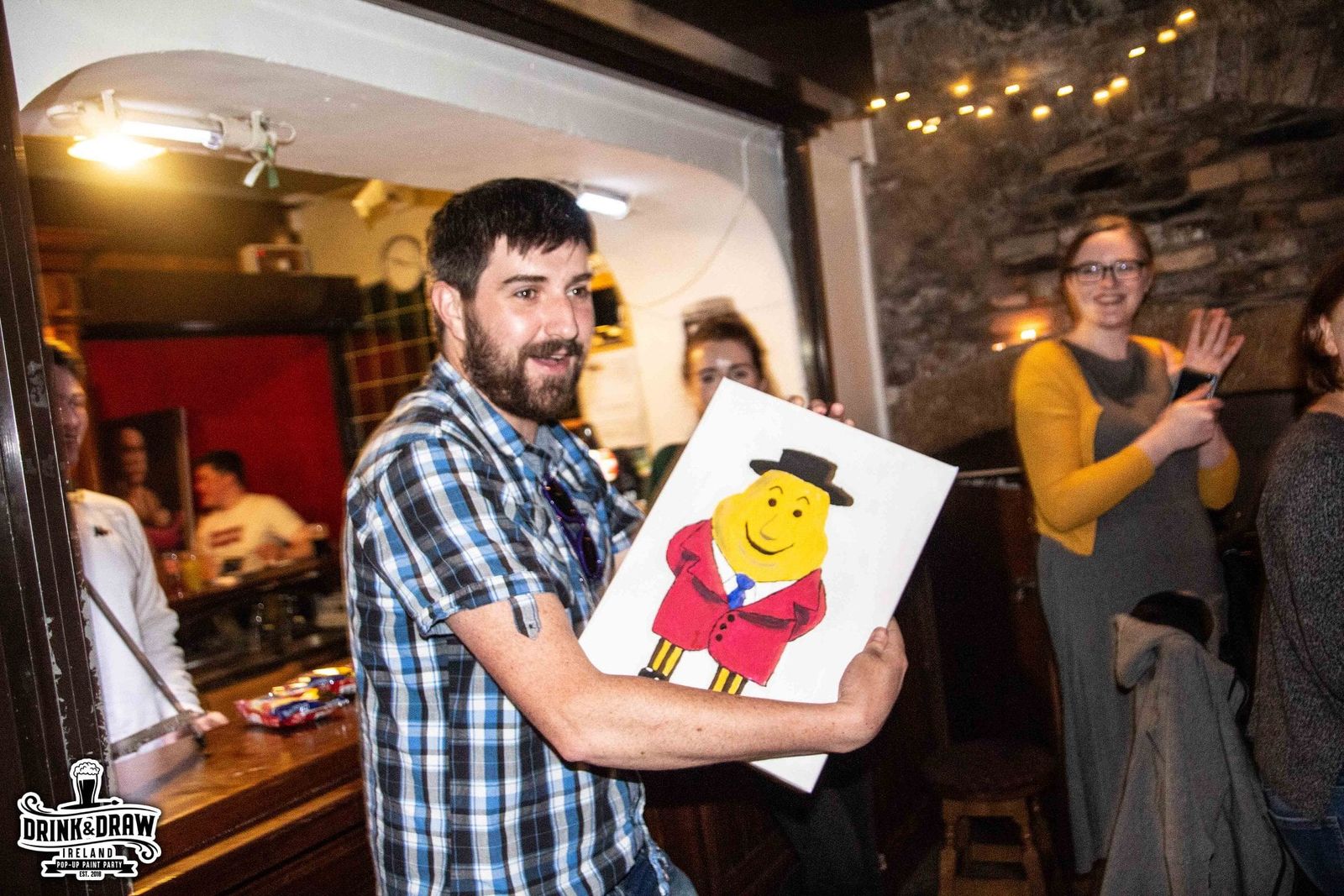 Guest holding up a cartoon portrait painting during a lively paint and sip event
